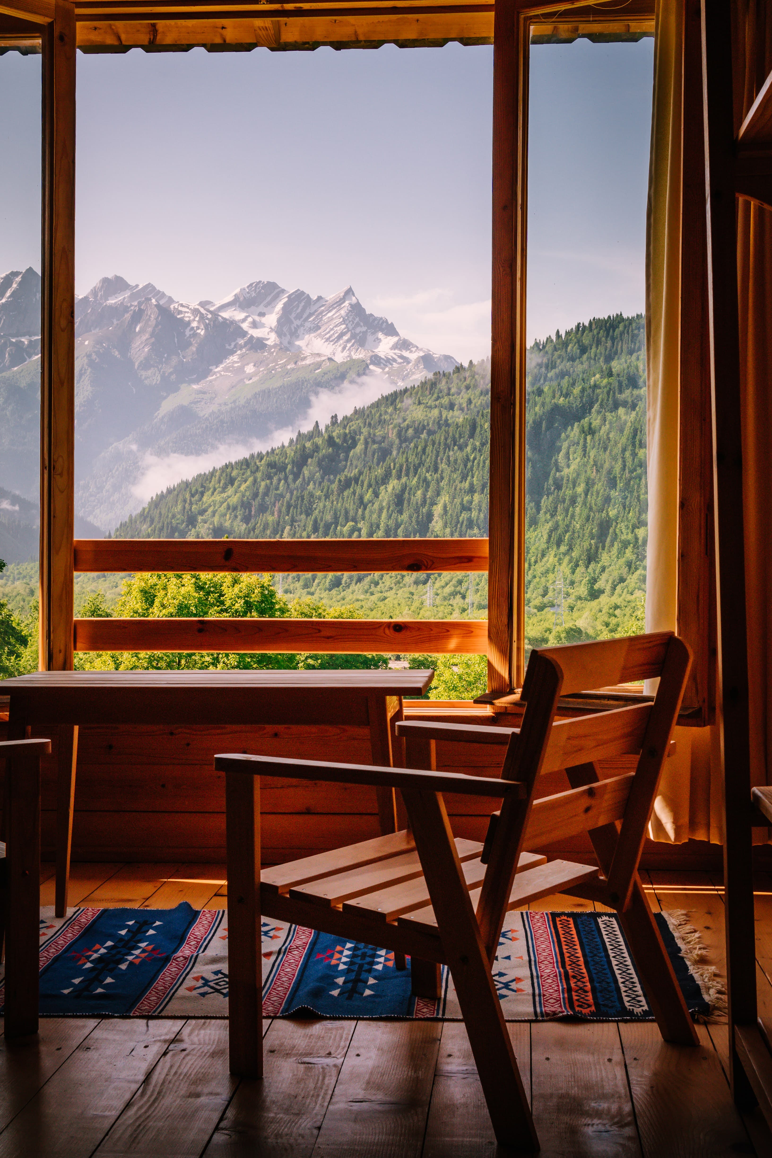 Handcrafted wooden chair facing snowy Caucasus peaks from Chiora Inn room